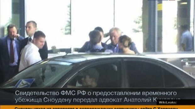Russian lawyer Anatoly Kucherena, second right in the centre, and Edward Snowden, centre back to a camera, as Snowden leaves Sheremetyevo airport outside Moscow, Russia.