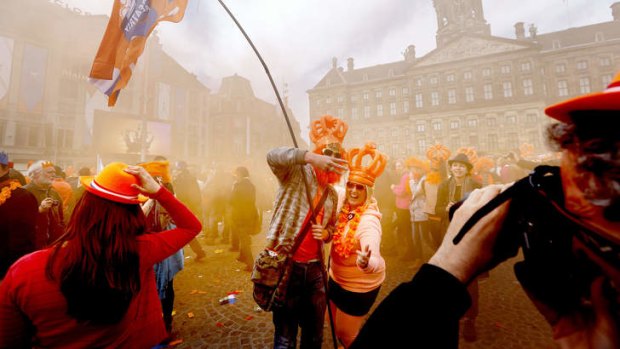 People, some of them wearing orange inflatable plastic crowns, celebrate on the Dam Square on the occasion of the investiture of the country's new king.