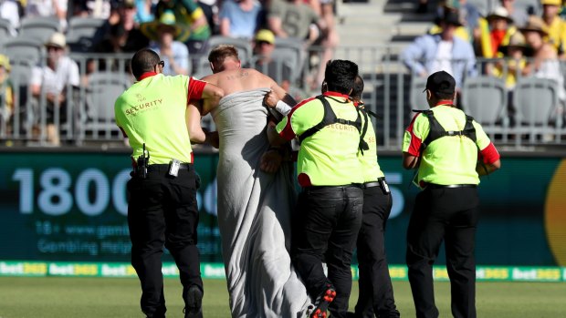 Walk of shame: A streaker is escorted off the ground by security.