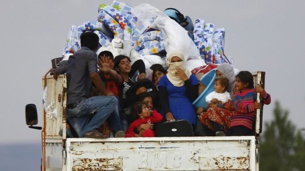 Syrian Kurdish refugees arrive on the back of a truck near the southeastern Turkish town of Suruc 