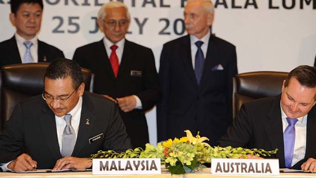 Malaysia's Home Minister Hishammuddin Hussein (L) and Australia's Immigration Minister Chris Bowen sign documents to swap thousands of refugees between the two countries.