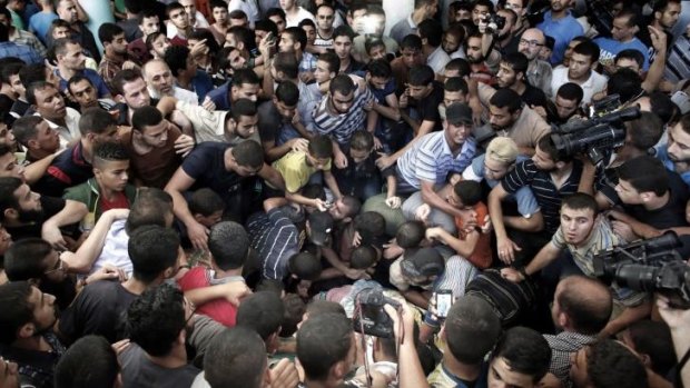 Palestinian Hamas supporters mourn over the body of one of three commanders.
