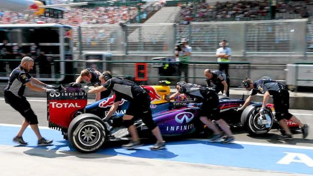 Mechanics push the car of Red Bull Racing's Australian driver Mark Webber into the pits during the third practice session at the Hungarian Grand Prix.