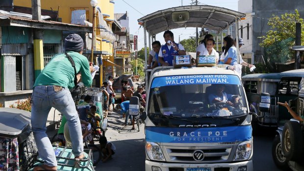 A supporter catches a souvenir T-shirt thrown by presidential candidate Senator Grace Poe, second from right, during her campaign sortie around Cavite province, south of Manila.