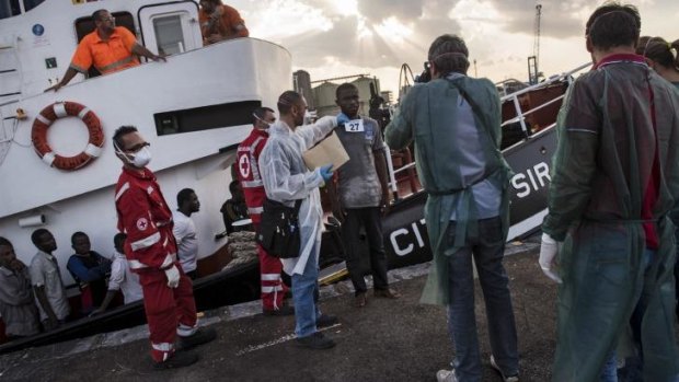 Processing: Refugees from Gambia, Nigeria, Ghana, Bangladesh, Afghanistan and other countries disembark an Italian commercial ship after being rescued at sea.