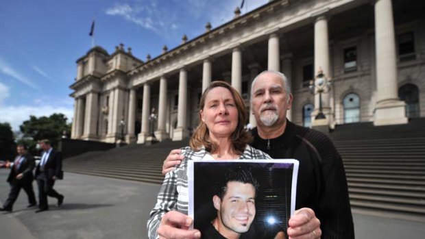 Deanna and Marco Papo hold a picture of their son Abraham outside Parliament.