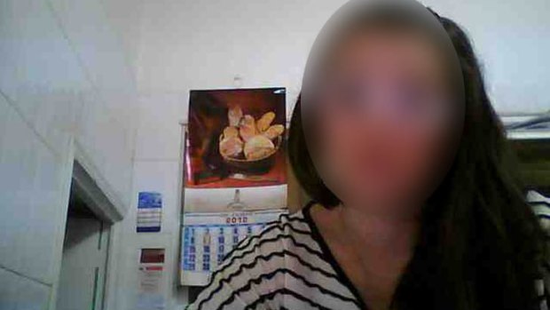 An image uploaded to a hacking forum showing a woman starting at her computer as seen through her webcam.