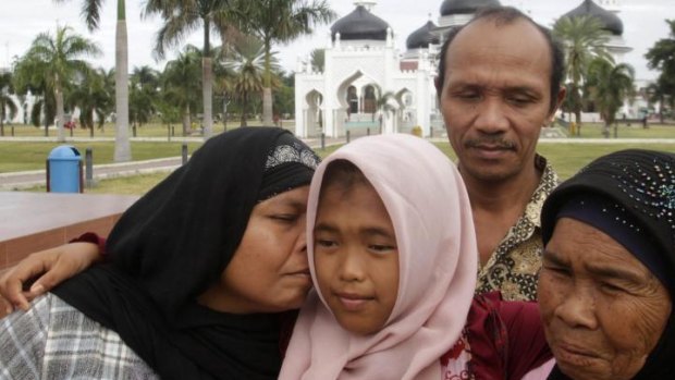 Jamaliah (left) kisses her daughter Raudhatul Jannah, 14, as the girl's father Septi Rangkuti and grandmother Sarwani look on following prayers at Baiturrahman mosque in Banda Aceh.