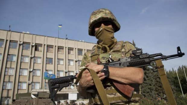 An Ukrainian soldier outside a government building with a Ukrainian flag on the roof in Slaviansk.