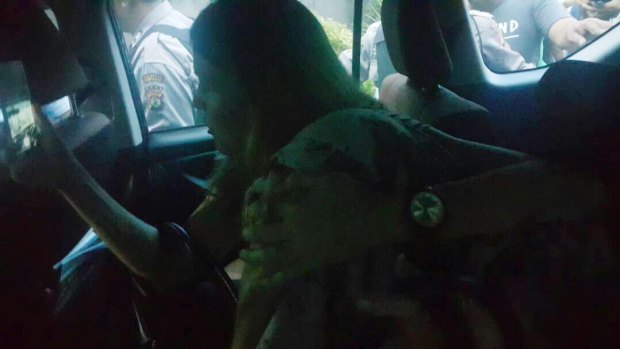 Mercedes Corby shields her sister Schapelle, who has her face covered, in the car taking her to the parole office.