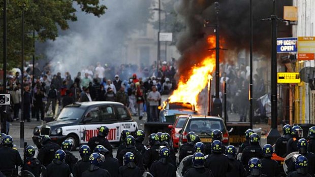 "This is sheer criminality" ... riot police block a road near a burning car in Hackney.
