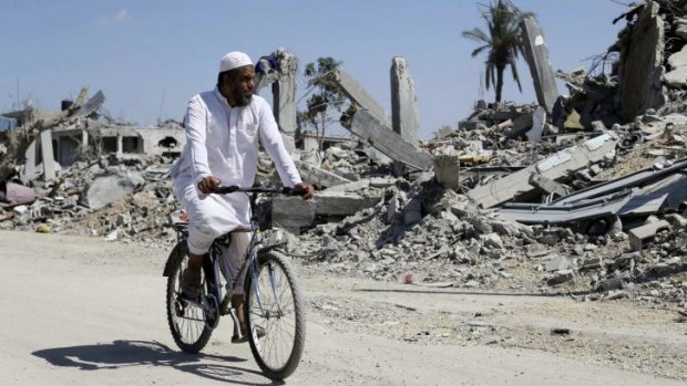 A Palestinian man cycles past the ruins of Khuza'a in the southern Gaza Strip.