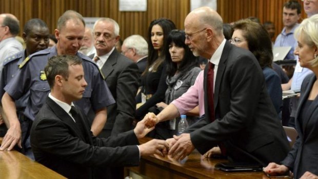 Oscar Pistorius greets his uncle Arnold Pistorius and other family members as he is led out of court.