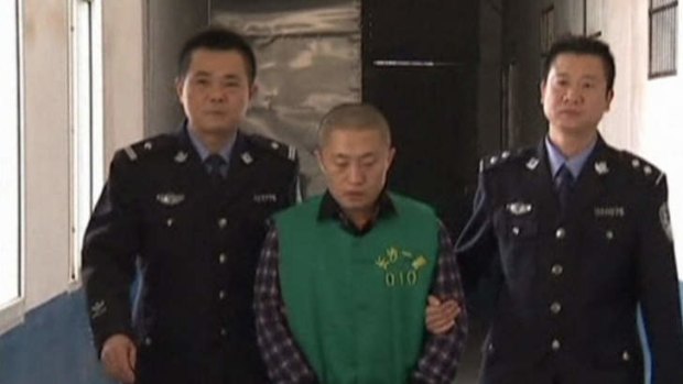 Journalist Chen Yongzhou, in handcuffs, is escorted by police officers in this still image taken from China Central Television.