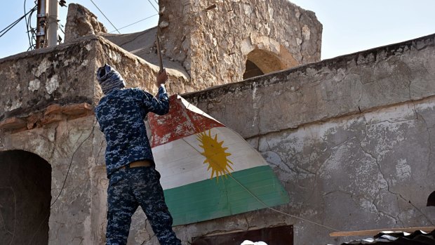 An Iraqi soldier removes a Kurdish flag from Altun Kupri on the outskirts of Irbil, Iraq.
