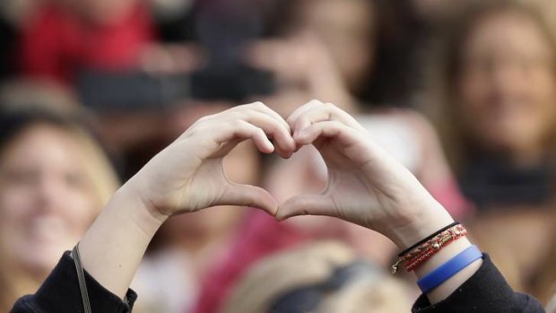 A fan holds her hands in the shape of a heart as Canadian singer Justin Bieber performs.