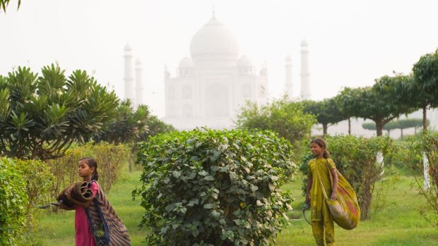 Girls work in the Mehtab Bagh (Moonlight Garden) in sight of the famous Taj Mahal palace.