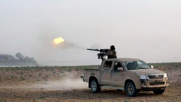 An Islamic State jihadist fires his weapon during a battle against Syrian government forces on a road between Homs and Palmyra, Syria. 