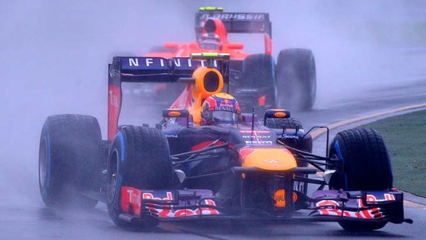 Formula one competitors drive around the track in pelting rain.