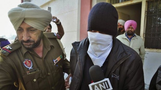 Fighting forced return to Australia ... Indian national Puneet Puneet, right, is escorted by a policeman as he is produced at a district court in Rajpura, in northern Punjab state, India.