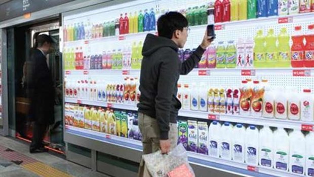A commuter makes a purchase on his phone, after browsing a virtual wall of groceries in Korea.