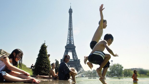 Children jump in the Trocadero fountains, in front of the Eiffel tower, in Paris.