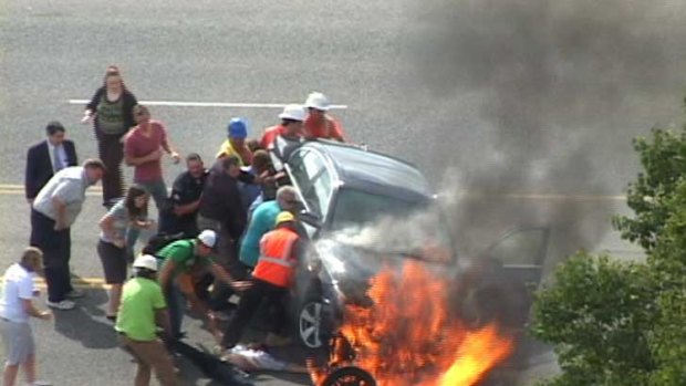 People lift the 1800 kilogram burning car off Brandon.