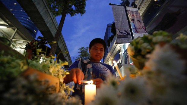 A man lights a candle near the Erawan Shrine at the Ratchaprasong intersection the day after an explosion in Bangkok.