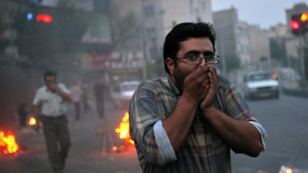 Defying ultimatum... demonstrators try to shield their faces from tear gas during clashes with riot police in Tehran.