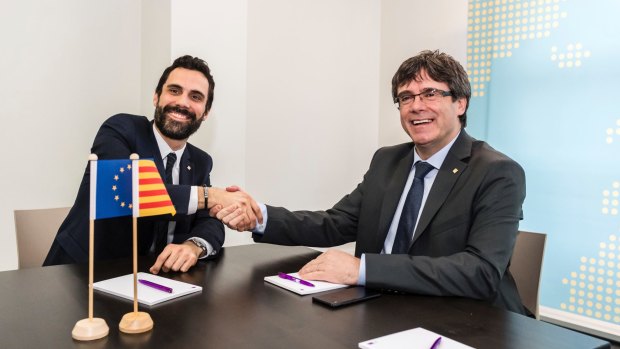 Ousted Catalan leader Carles Puigdemont, right, shakes hands with the President of the Parliament of Catalonia Roger Torrent in Brussels.