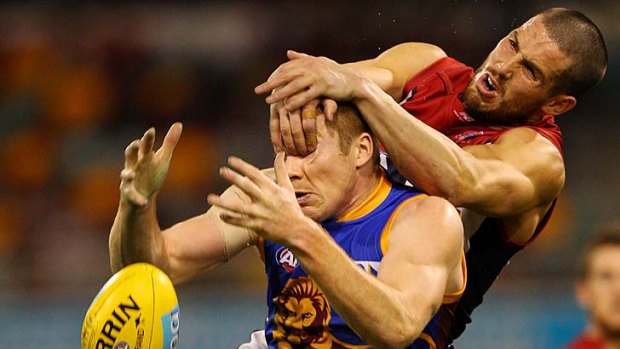 Eye tackle: Brisbane's Ryan Harwood gets an accidental hand in the the face from Demon James Magner yesterday.