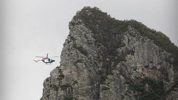 A helicopter moves in to rescue a female rock climber who fell from Mt Coonowrin in the Glasshouse Mountains.