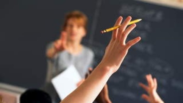 Teacher pointing to raised hands in classroom boarding school  Generic