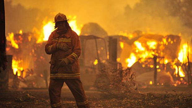 A firefighter stands in the debris as a bushfire rages in the Bunyip area. Picture: Jason South.