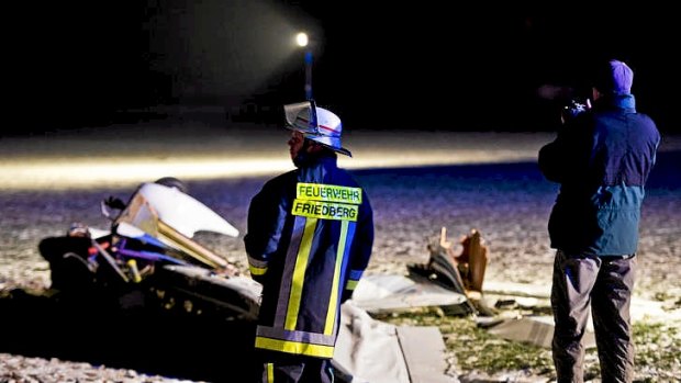 A firefighter (left) stands near a wreck of a light aircraft which crashed into another plane at Woelfersheim, Germany.