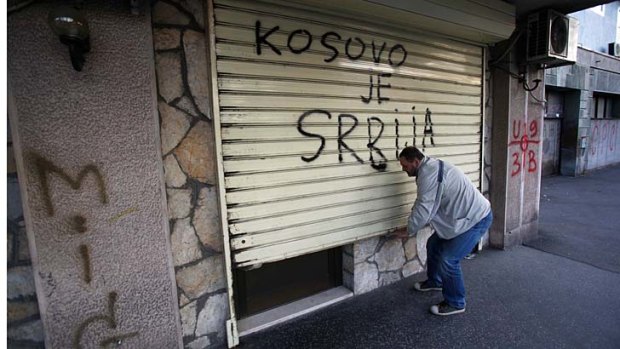 A man closes a shutter with graffiti reading: "Kosovo is Serbia" in Belgrade, Serbia. Serbia and Kosovo reached a potentially historic agreement on Friday to normalise relations between the Balkan neighbours.