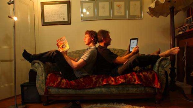 Graham Cottew (right), reading a book on his i-pad, while his 19-year-old son Tim prefers a paper book.