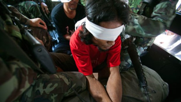 An anti-government protester is detained by Thai security forces.