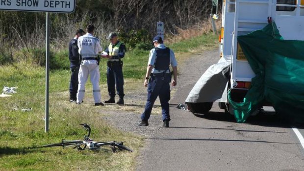 Fatal accident: police examine the scene where a cyclist died after he was involved in a collision with a truck.