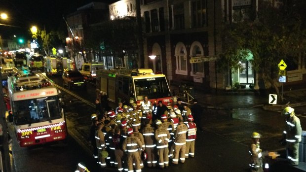 Firefighters gather on Darling Street in Rozelle, after finding a man's body among the rubble.