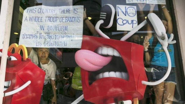 Protesters watch from the relative safety of a McDonald's restaurant during anti-coup protests in Bangkok on Sunday.