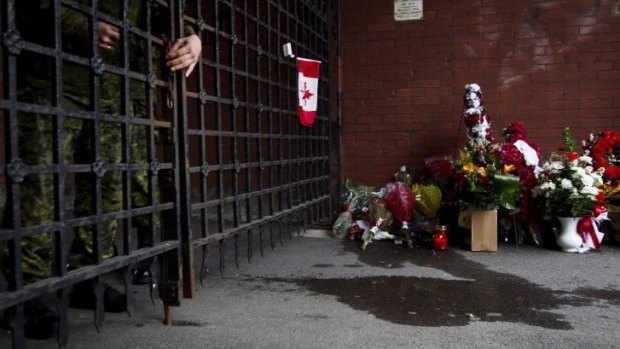 A soldier locks the gates as flowers are placed at a memorial outside the gates of the John Weir Foote Armory.