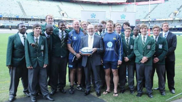 Brumbies coach Jake White and South African born winger Clyde Rathbone with University of Canberra Vice Chancellor Stephen Parker and rugby players from Kingsway High School.