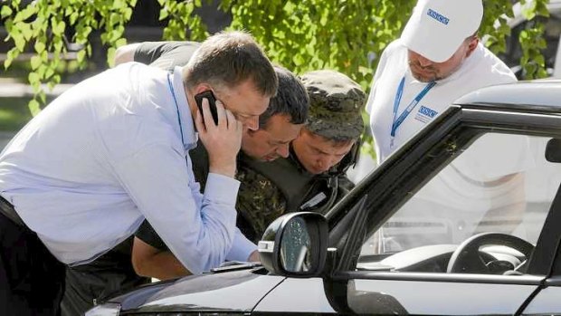 Alexander Hug, deputy head of the OSCE mission to Ukraine, left, his colleagues and a pro-Russian rebel, second right, examine a map as they try to estimate security conditions around the site of the crashed Malaysia Airlines Flight 17.