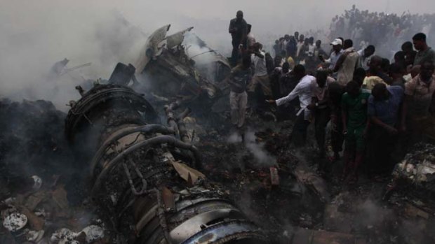 Smouldering wreckage ... onlookers and soldiers inspect the site of the Nigerian plane crash which claimed more than 150 lives.