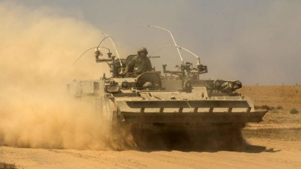 An Israeli soldier drives an armoured personnel carrier to take position at the border with Gaza.