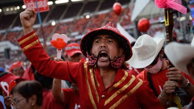 A Thai pro-government Red Shirt supporter in traditional costume shouts slogans during a rally at a stadium in Bangkok.