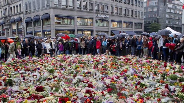 People gather to offer flowers in tribute to the victims of Friday's twin attack in Oslo outside the cathedral of Oslo.