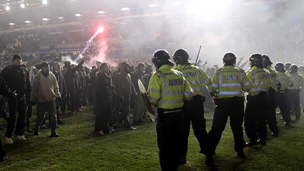 Hostility fires up ... riot fans confront Birmingham fans after they invaded the pitch and hurled flares at the visiting Aston Villa supporters.