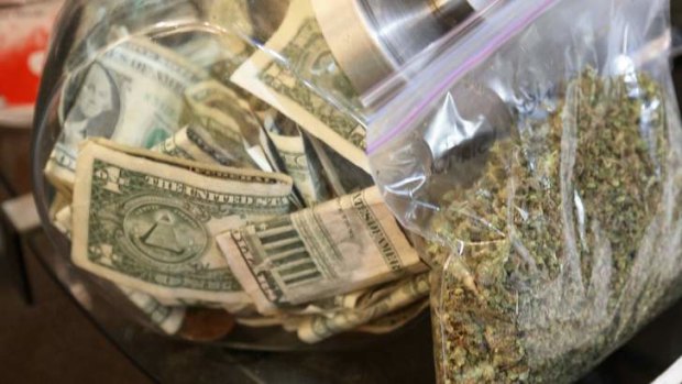 Rolling in money: A bag of marijuana being prepared for sale sits next to a money jar at BotanaCare in Colorado.
